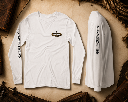 Nail & Crown Co. unisex long sleeve t-shirt in white with nail and crown logo on chest and Nail & Crown Co. branding on sleeve, flat lay on aged parchment with rope and leather